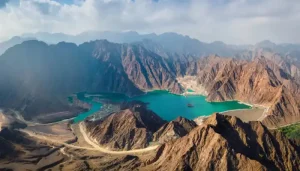 Aerial landscape view of a turquoise dam surrounded by rocky mountains.