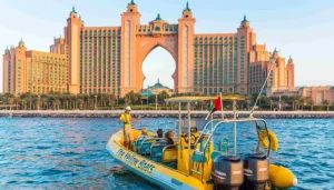 Findanyagent Dubai travel guide showing a yellow sightseeing boat tour in front of Atlantis The Palm resort.