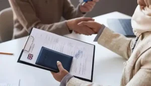 Client shaking hands with a visa agent holding an approved visa application and passport.