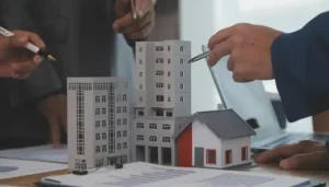Commercial real estate professionals pointing at miniature building models during a business consultation.