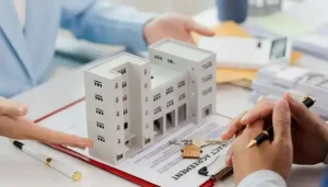 Dubai commercial property agent presenting a miniature office building model, contract agreement, and keys during a meeting.